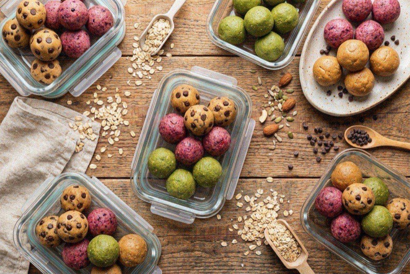 Round protein cookie dough balls with chocolate chips on a parchment-lined tray