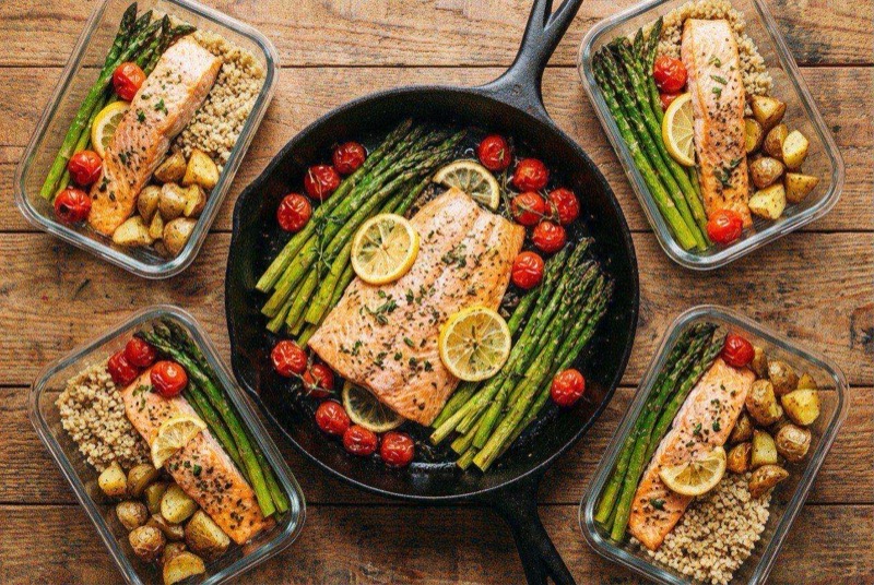 Golden-seared salmon fillet next to bright green asparagus in a skillet with lemon and butter