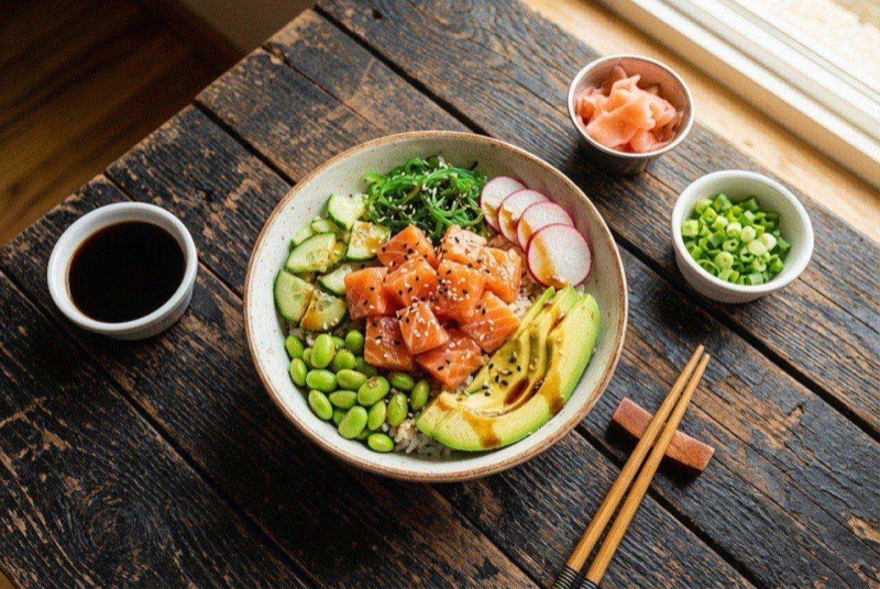 Colorful poke bowl with cubed salmon, avocado slices, edamame, cucumber, and sesame seeds over rice