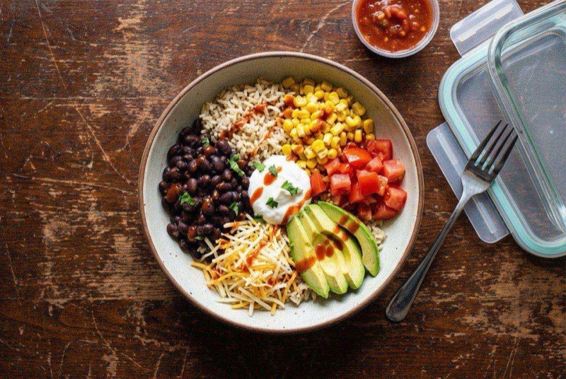 Simple burrito bowl in a microwave-safe bowl with rice, black beans, chicken, melted cheese, and salsa