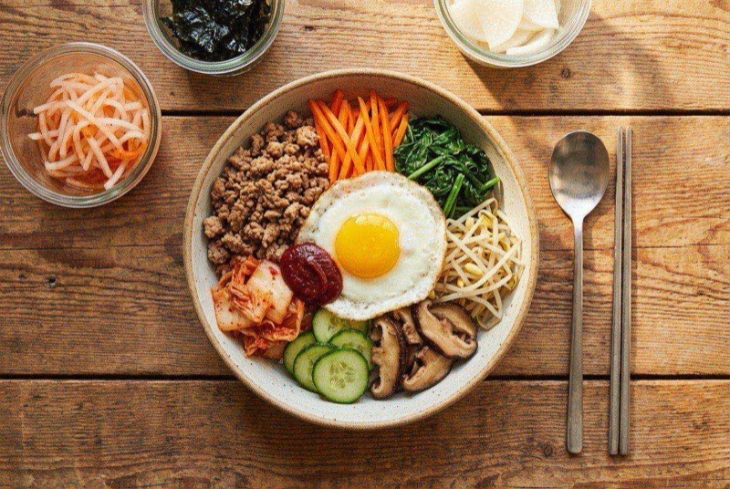 Colorful bibimbap bowl with ground turkey, assorted vegetables, a fried egg, and red gochujang sauce