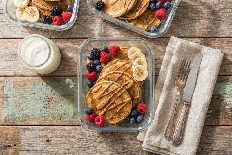 Stack of golden protein pancakes with fresh berries and a drizzle of maple syrup