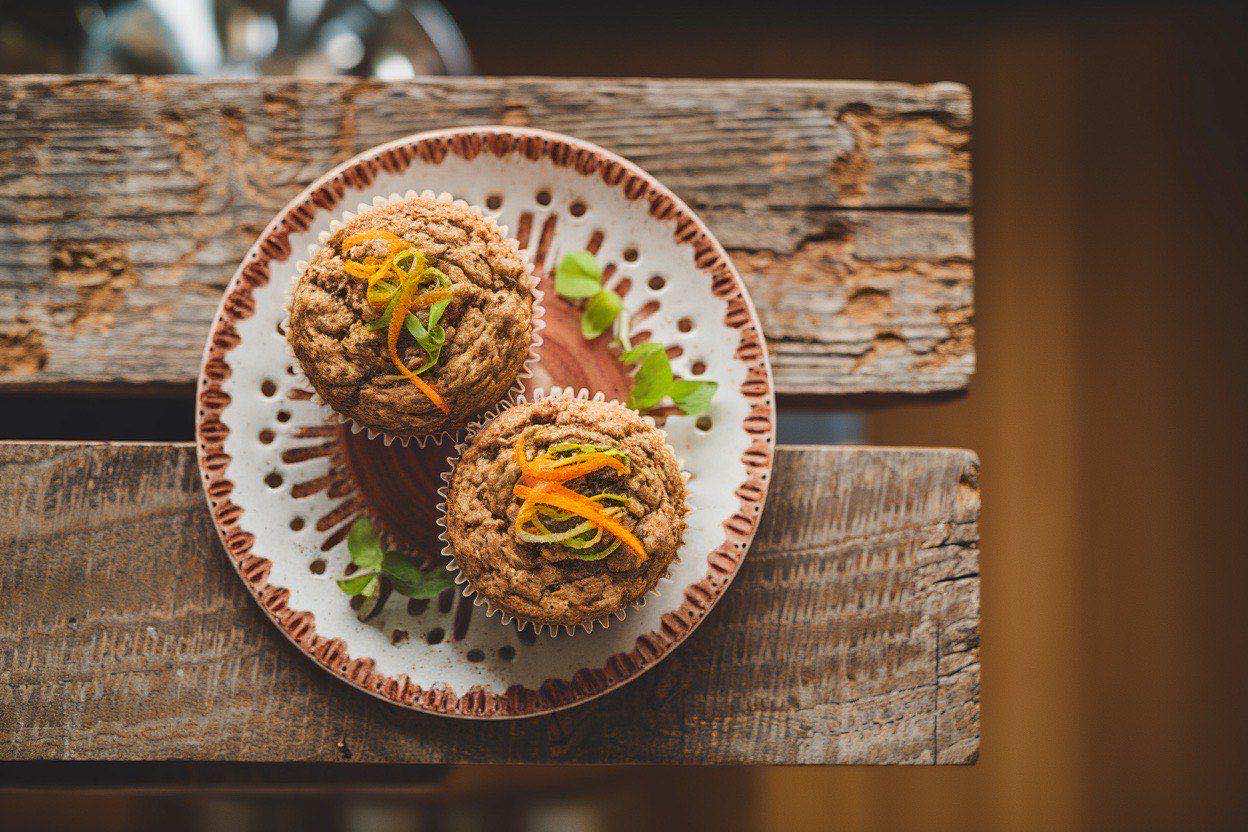 Dark golden bran muffins with visible raisins arranged on a cooling rack with a linen napkin