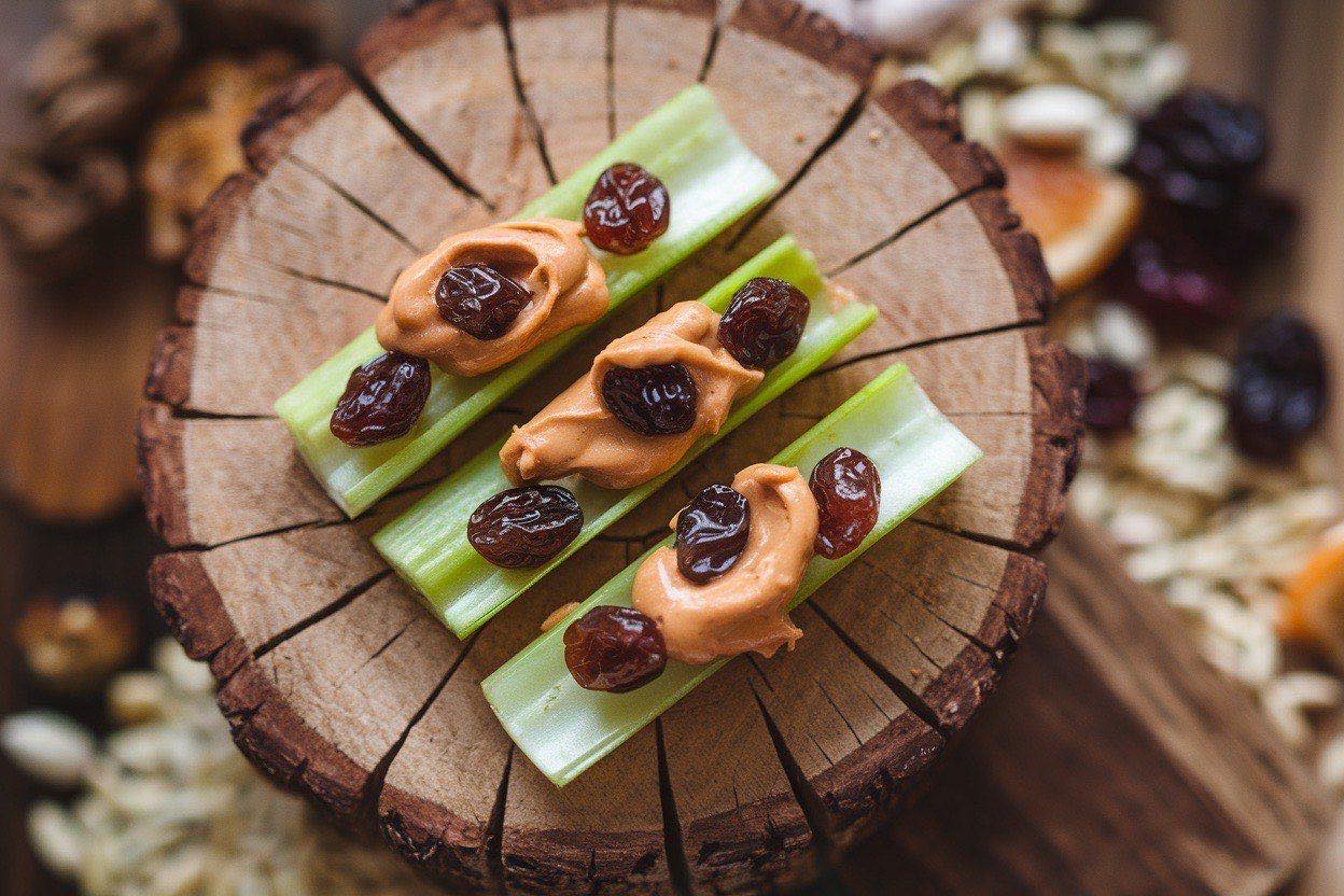 Celery sticks filled with peanut butter and dotted with raisins arranged on a colorful plate