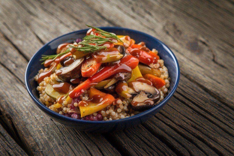 Grain bowl with colorful roasted broccoli, sweet potato cubes, and chickpeas drizzled with tahini
